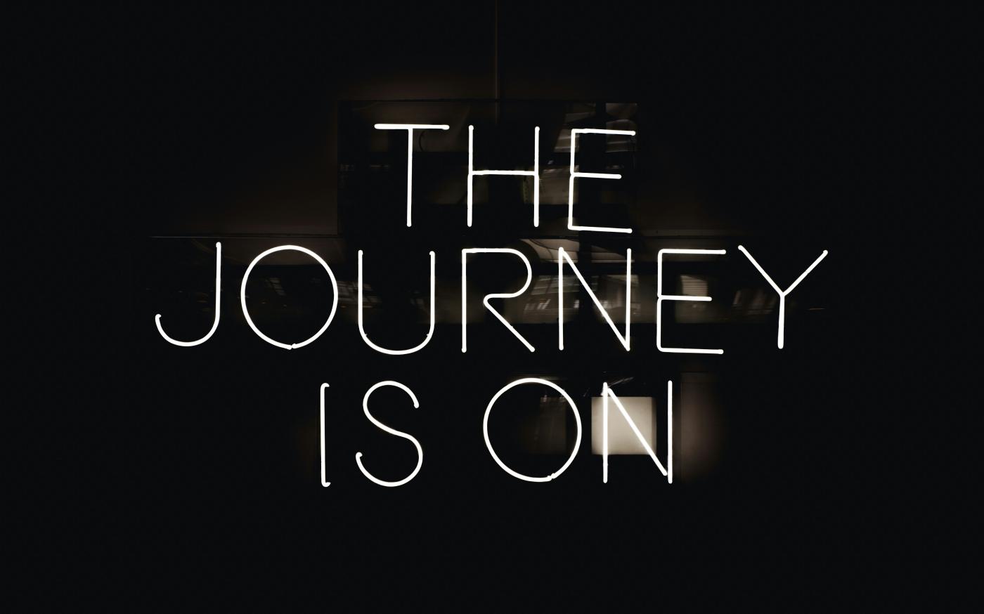 a black and white photo with the words the journey is on by Maxime Horlaville courtesy of Unsplash.